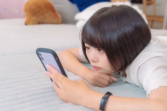 LINEが既読にならないなと、スマートフォンを見続けてしまう女性の写真